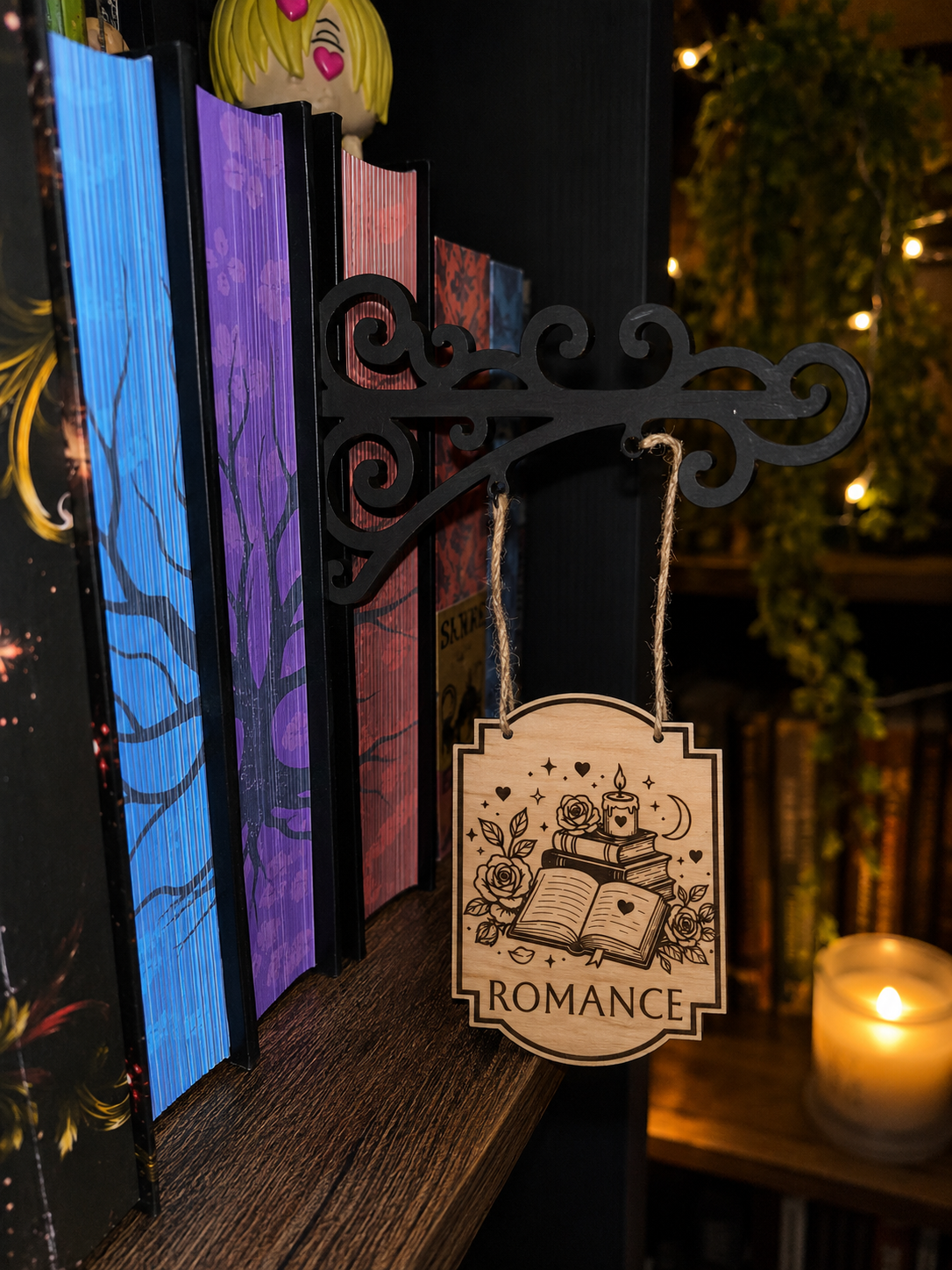 Séparateur d'étagère suspendu en bois gravé thème romance accroché à une bibliothèque remplie de livres colorés.