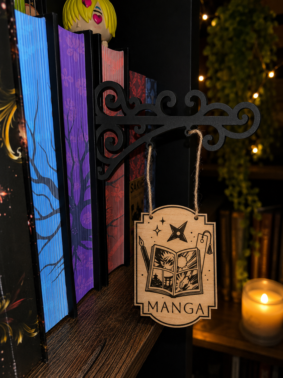 Séparateur d'étagère suspendu en bois gravé thème Manga accroché à une bibliothèque remplie de livres colorés.