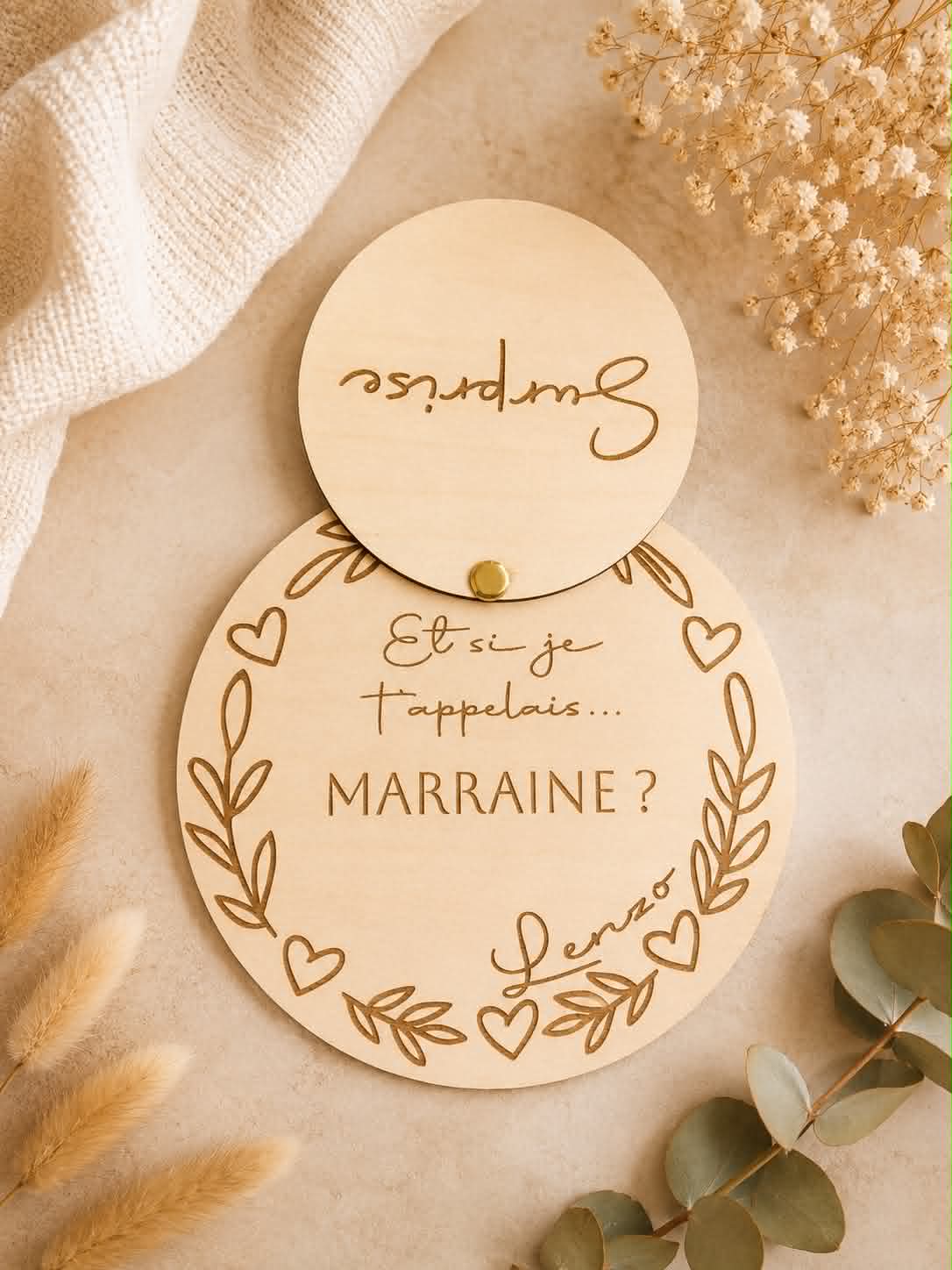 Plaque en bois personnalisée avec disque pivotant "Surprise" révélant une demande de marraine gravée, décorée de feuilles et de cœurs.