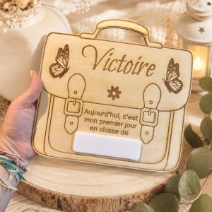 Immortalisez le premier jour d'école avec ce tableau cartable personnalisé en bois. Réutilisable chaque année grâce à sa plaque effaçable. Fabrication artisanale.