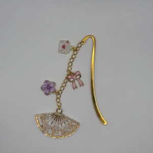 Marque-page en métal doré décoré d'un éventail ajouré, d'une fleur violette, d'un nœud rose et d'une enveloppe suspendue, idéal pour les passionnés de lecture.
