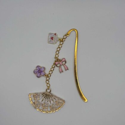 Marque-page en métal doré décoré d'un éventail ajouré, d'une fleur violette, d'un nœud rose et d'une enveloppe suspendue, idéal pour les passionnés de lecture.