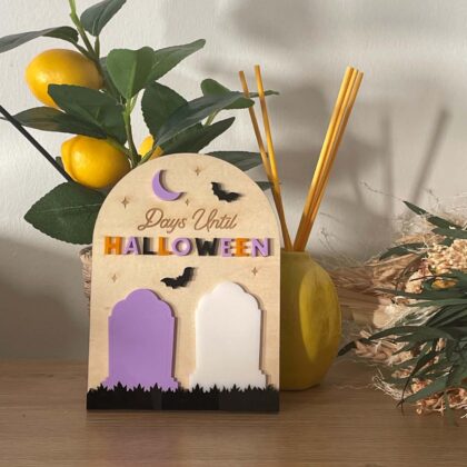 Compteur de jours avant Halloween en bois, décoré de pierres tombales colorées, chauves-souris et lune, avec deux emplacements pour afficher le nombre de jours restants.